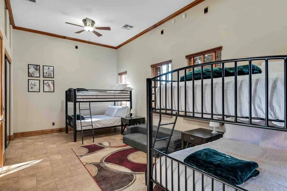 A bedroom designed for group or family stays, featuring cozy bunk beds, a soft rug, and cheerful wall artwork. The space is warm, inviting, and perfect for younger guests or groups seeking togetherness and fun sleepovers.