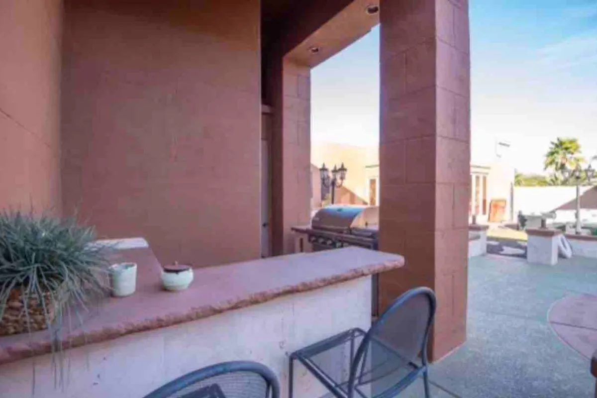 A welcoming exterior barbecue area featuring a grill, bar seating, potted plants, and a cozy seating nook. The space exudes a casual, social mood and is ideal for barbecues and evening gatherings with friends.
