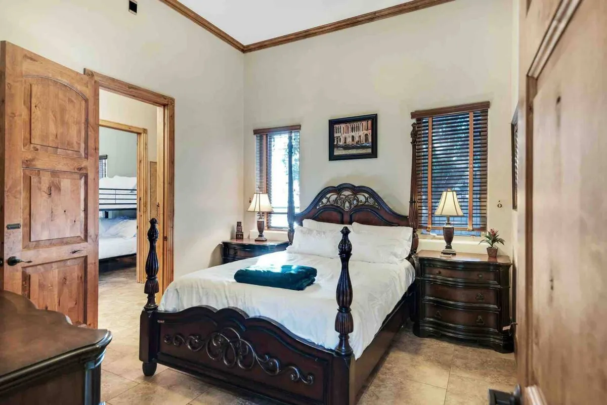 A cozy bedroom with an ornate wooden bed, nightstands topped with lamps, and decorative wall art. The soft lighting creates a welcoming and restful atmosphere, showcasing the room as a comfortable haven for relaxation and quiet moments.