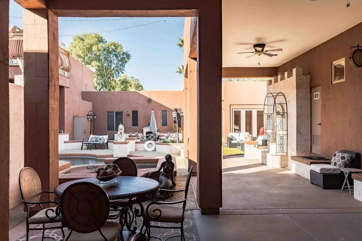 An inviting outdoor dining area positioned by the pool. The scene captures a round dining table set for al fresco meals, surrounded by comfortable seating and overlooking the tranquil pool, ideal for gatherings and sunset dinners.