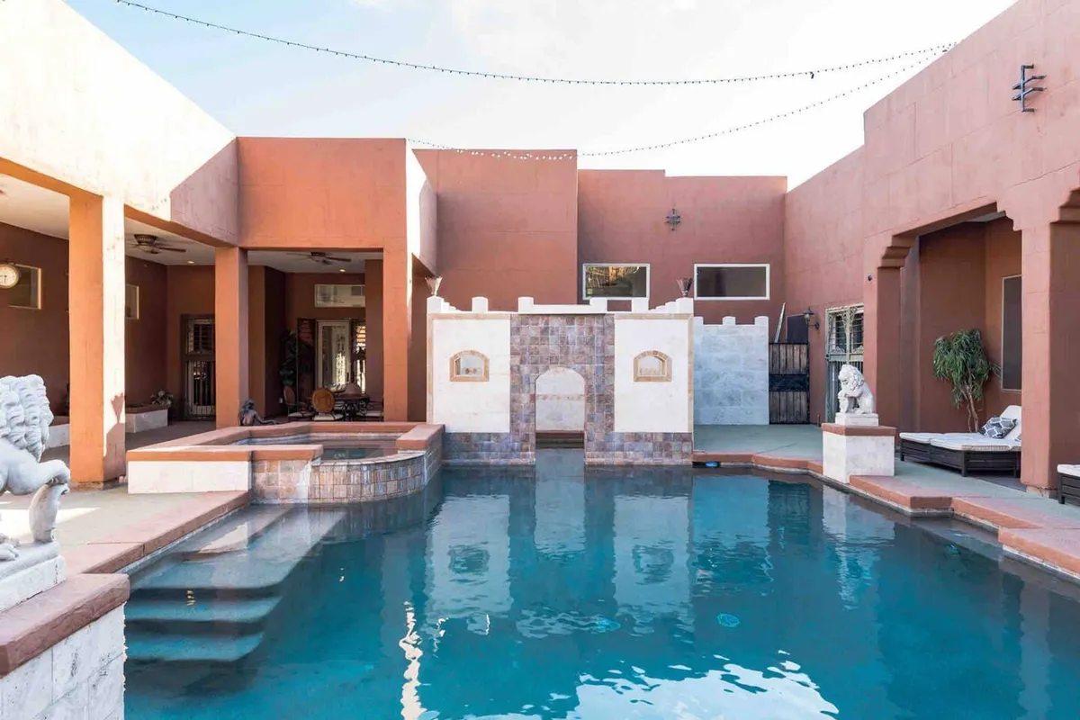 The serene outdoor pool area is framed by a decorative wall and statues, hinting at both relaxation and the opportunity for festive celebrations. Evening lighting and lush surroundings add to the resort-like ambiance.
